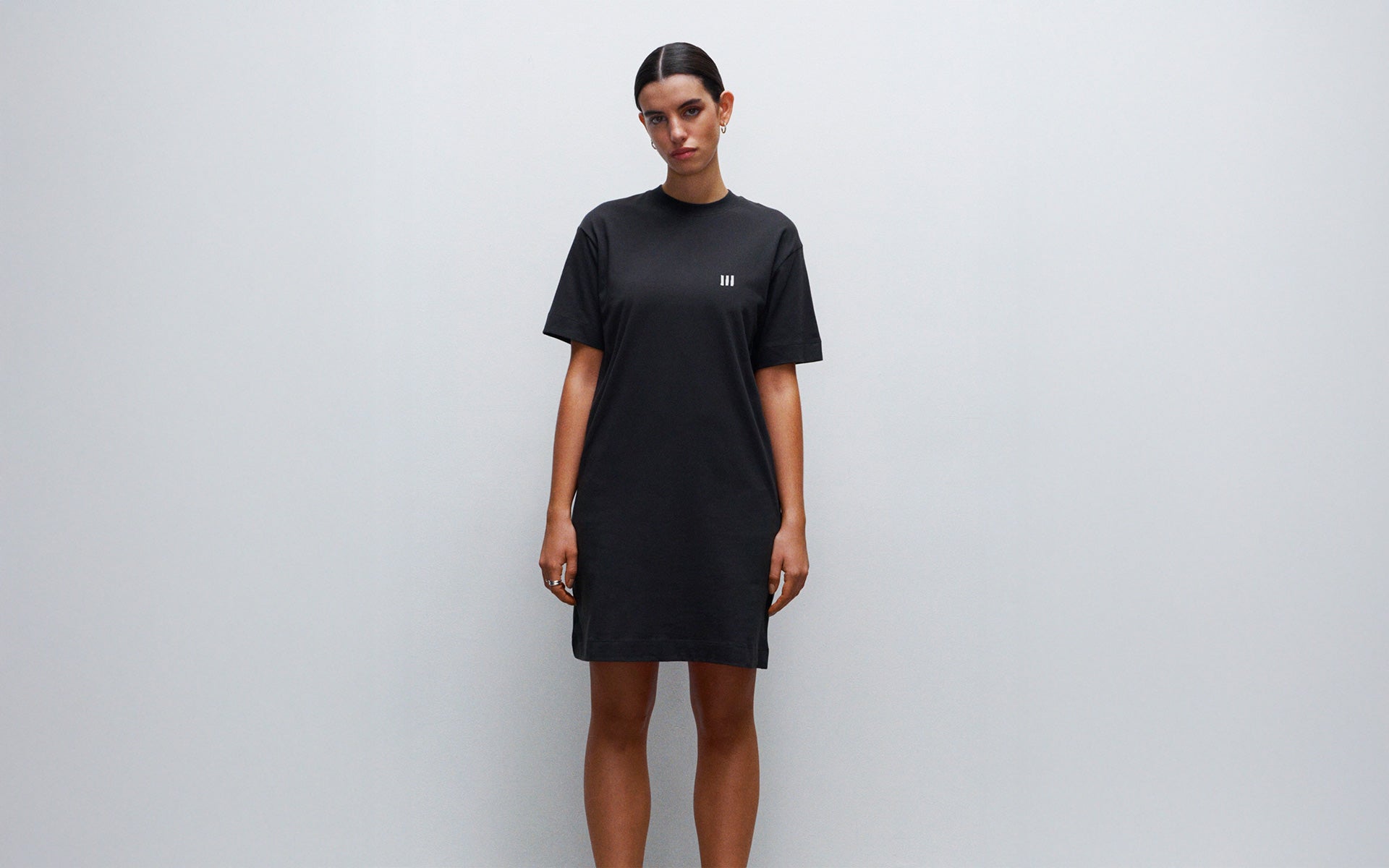 Woman wearing a black t-shirt dress against a plain background